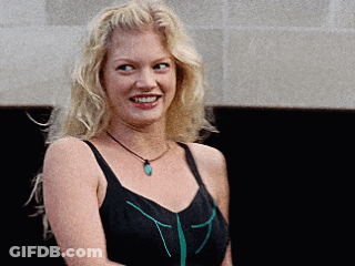 Blonde Woman In Black Tank Top And Green Necklace Smiling GIF