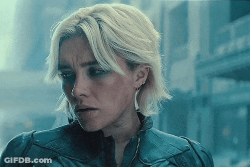 Blonde Woman In Blue Jacket And Earrings GIF