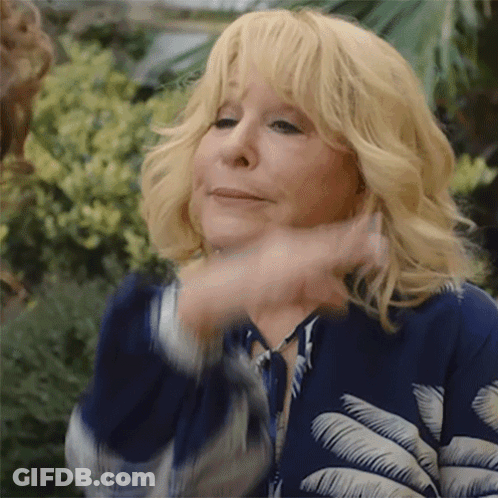Blonde Woman In Blue Jacket With Palm Leaves Making Funny Face GIF