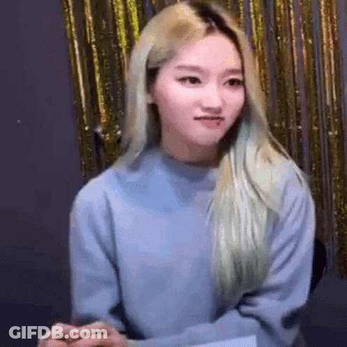 Blonde Woman In Blue Sweater Before Gold Curtain GIF