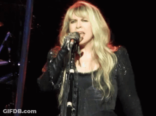 Blonde Woman Singing Into Microphone On Stage GIF