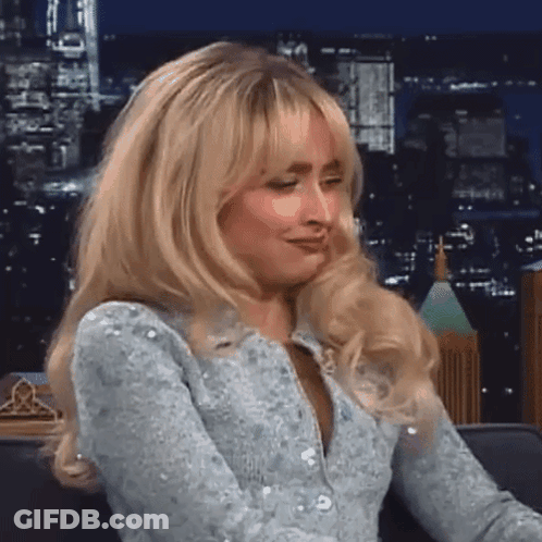 Blonde Woman Sitting On Couch Before City Skyline GIF