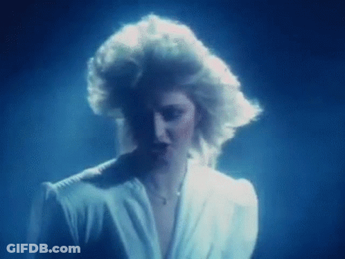 Blonde Woman Standing In Dark Room With Blue Light GIF