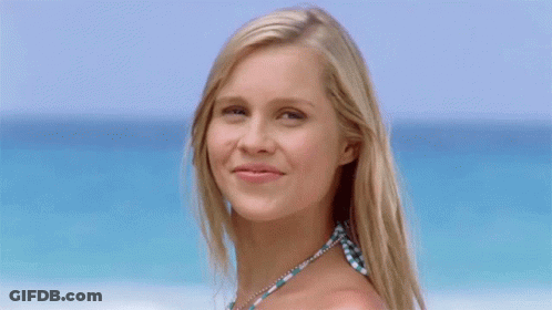 Blonde Woman Waving Hand In Front Of Ocean GIF