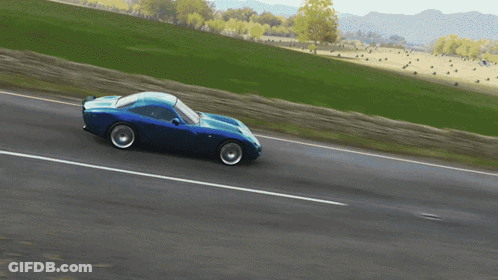 Blue Car Driving Down Road With Grassy Field GIF