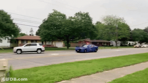 Blue Car Driving Down Street Next To White SUV And House GIF