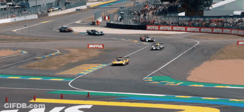 Blue Car Driving Down Street Past Crowd GIF