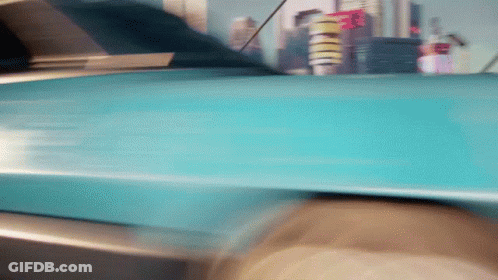 Blue Car Driving Down Street With City Skyline GIF
