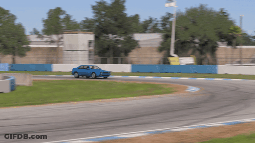 Blue Car Driving On Race Track With Blue And White Fence GIF