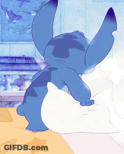 Blue Cartoon Character Laying On Bed With White Pillow GIF