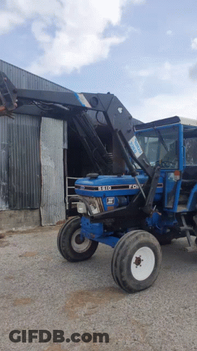 Blue Ford Tractor Parked Outside Building GIF
