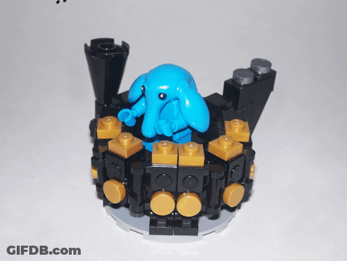 Blue Lego Figure Sitting On Black And Gold Block GIF