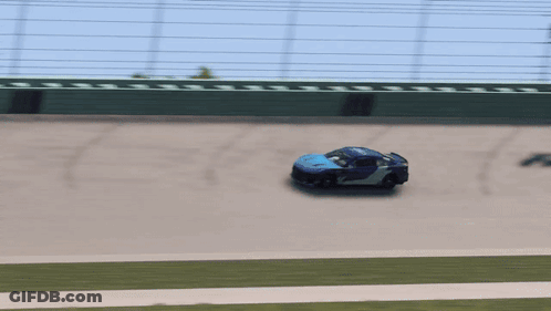 Blue Race Car Driving On Track With Green Fence GIF