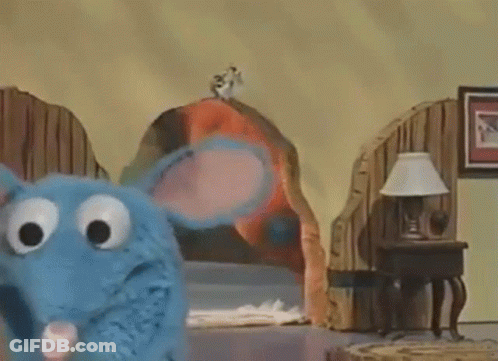 Blue Stuffed Animal Standing Next To Bed And Lamp GIF