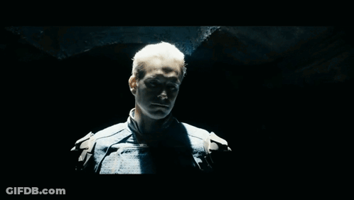 Blue-Suited Man Looking At Camera In Dark Room GIF