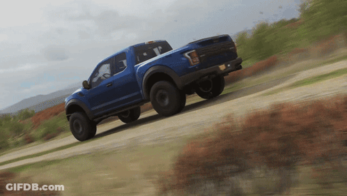 Blue Truck Driving On Dirt Road With Mountains GIF