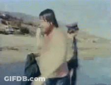 Blurry Man On Beach With Cat Behind Him GIF