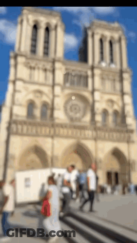 Blurry People Walking By Tall Building GIF