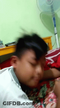 Blurry Person Laying On Bed With Fan GIF