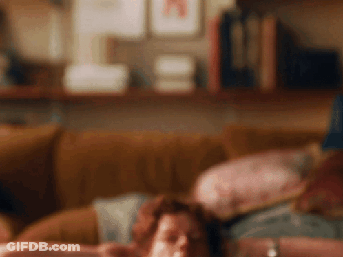 Blurry Person Laying On Couch With Bookshelf GIF
