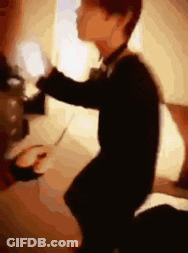 Blurry Person Sitting On Bed With Remote GIF