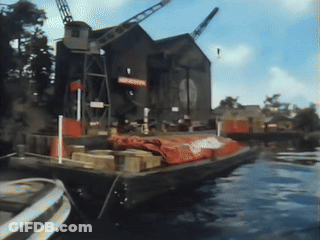 Boat In Water With Warehouse Sign GIF