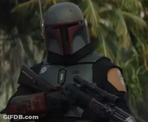 Boba Fett Is Wearing A Helmet And Holding A Gun In A Forest . GIF