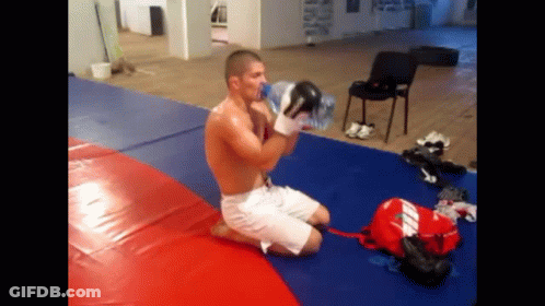 Boxer Drinking Water While Kneeling On Mat GIF