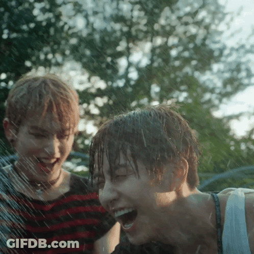 Boy And Girl Laughing Under Sprinkler GIF