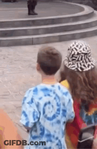 Boy And Girl Standing Next To Each Other Looking At Statue GIF