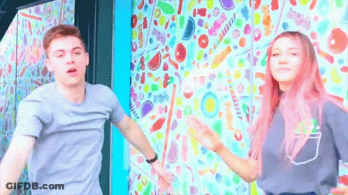 Boy And Girl With Pink Hair Dancing In Front Of Candy Wall GIF