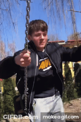 Boy In Black Jacket And An T-Shirt Swinging On Chain GIF