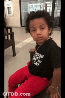 Boy In Black Shirt And Red Pants Sitting On Chair GIF
