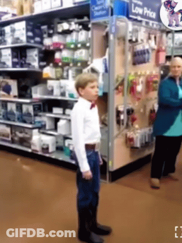 Boy In Bow Tie In Front Of Low Price Sign GIF