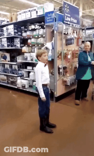 Boy In Bow Tie Standing Before Low Price Sign GIF