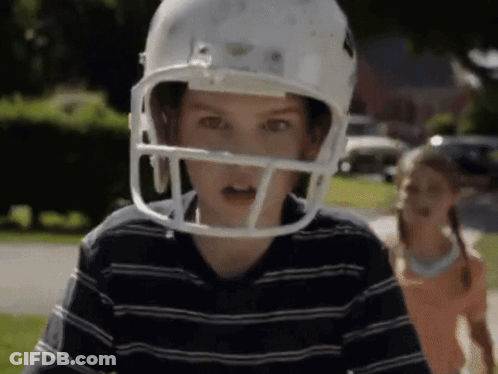 Boy In Football Helmet With Girl Behind GIF
