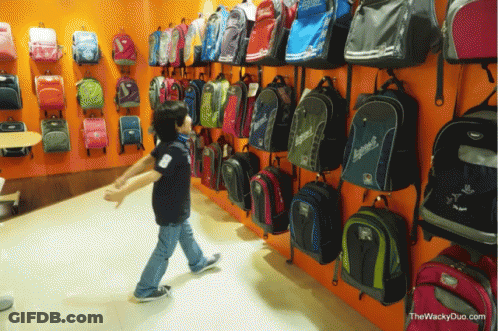 Boy In Front Of Wall Of Backpacks With Explorer GIF
