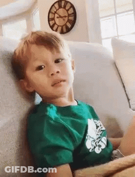 Boy In Green Shirt Sitting On Couch With Clock GIF