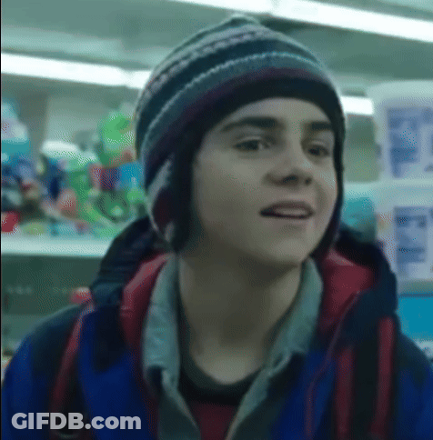 Boy In Hat And Blue Jacket In Front Of Store Shelf GIF