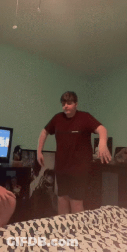 Boy In Maroon Shirt Standing In Front Of TV GIF
