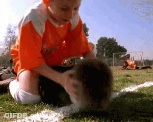 Boy In Orange Shirt Kneeling On Soccer Field GIF