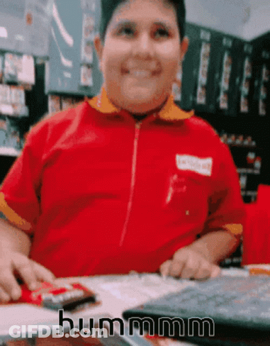 Boy In Red Shirt Sitting At Table Saying Hummm GIF