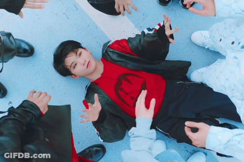 Boy In Red Shirt With Smiley Face Laying On Ground GIF