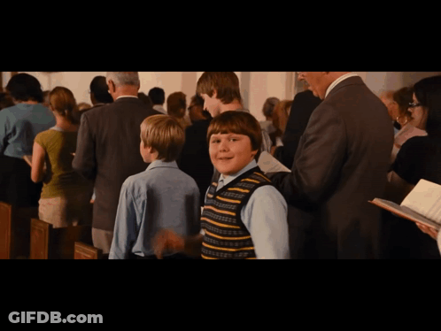 Boy In Striped Vest Standing In Crowd GIF