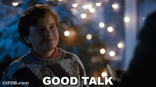 Boy In Sweater Says Good Talk Beside Christmas Lights GIF