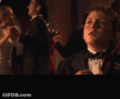 Boy In Tuxedo Standing In Front Of Hold On A Second Guys Sign GIF