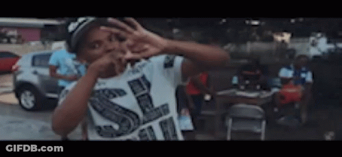 Boy In White Shirt With Letter S Making Peace Sign GIF