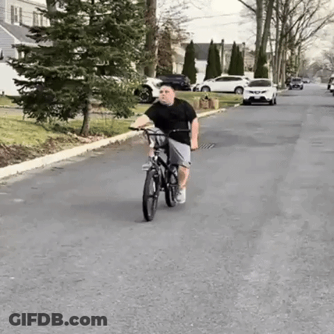 Boy Riding Bike Down Street GIF