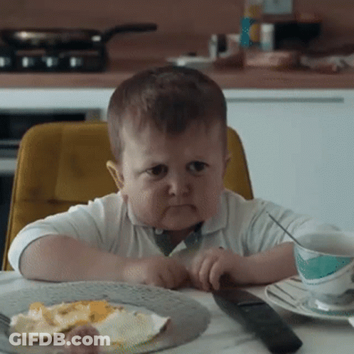 Boy Sitting At Table With Food And Remote GIF