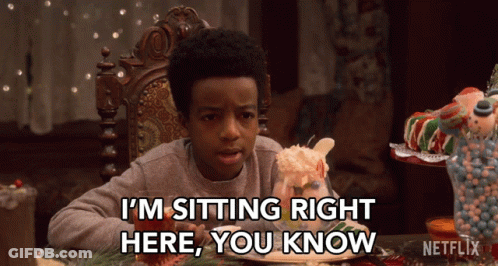 Boy Sitting At Table With Gingerbread House Says I'm Sitting Right Here You Know GIF
